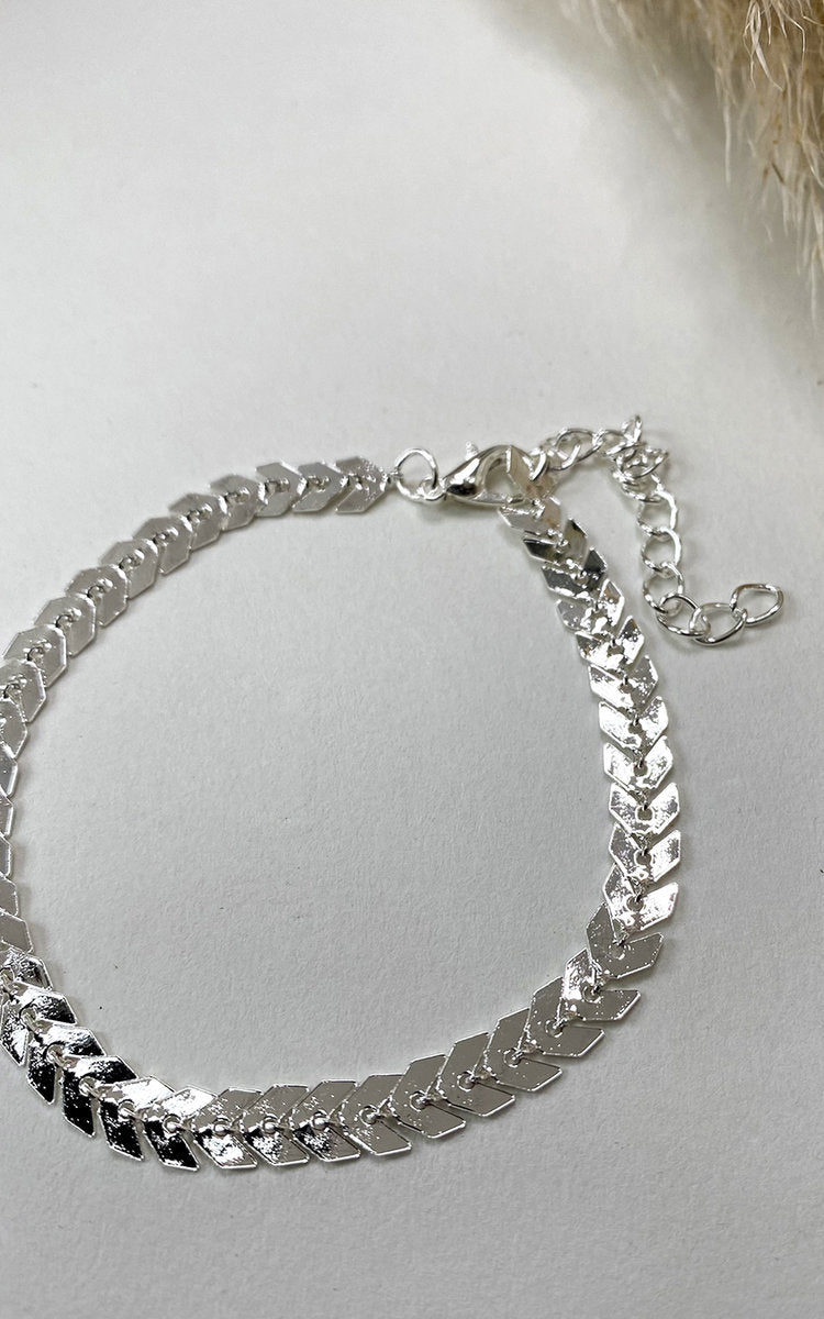 Chevron Anklet by Clarizzma in silver. Features a delicate chain with a chevron pendant design and an adjustable clasp for a perfect fit.